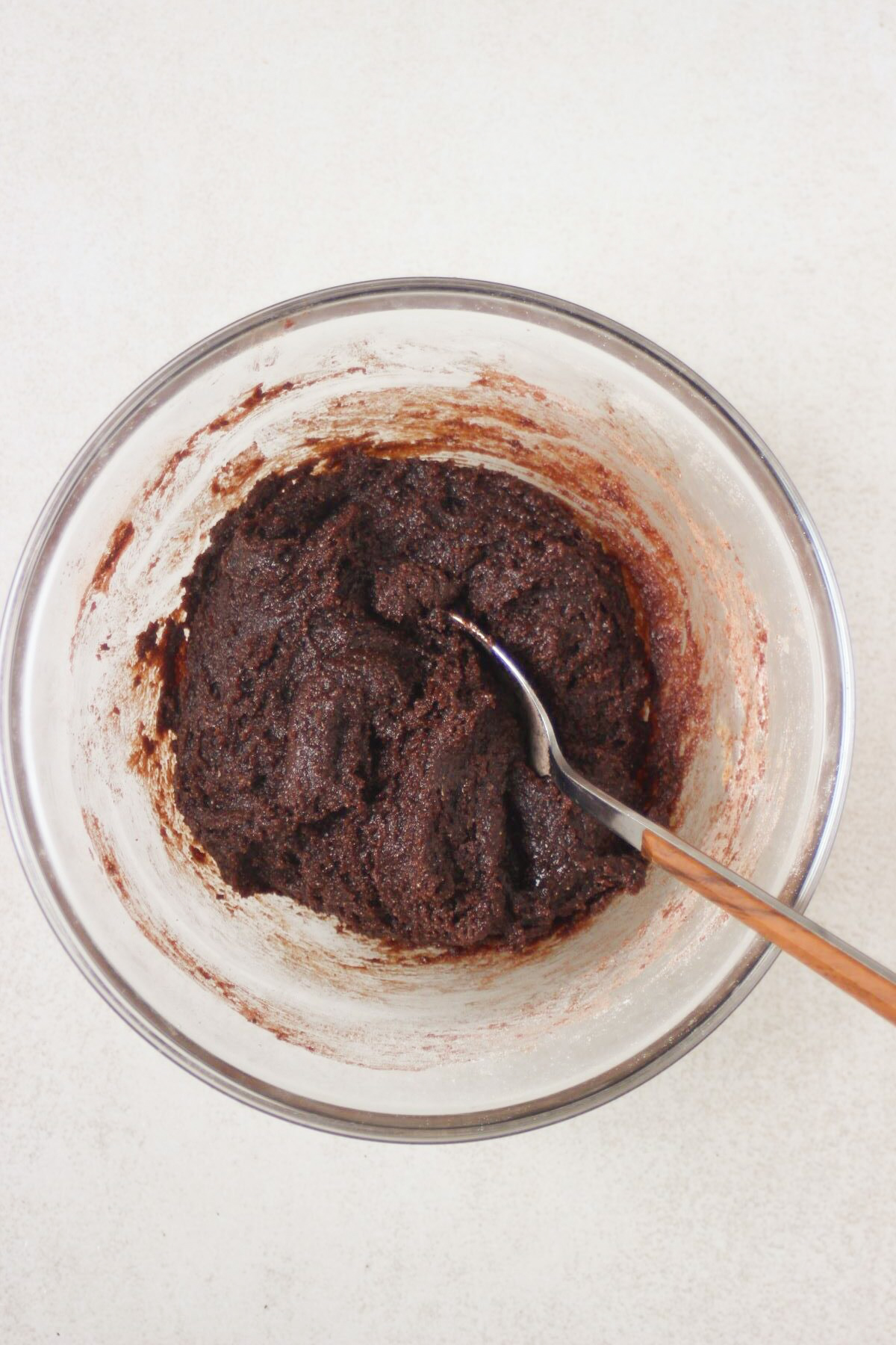 Glass bowl with a smooth brown mixture and a spoon.