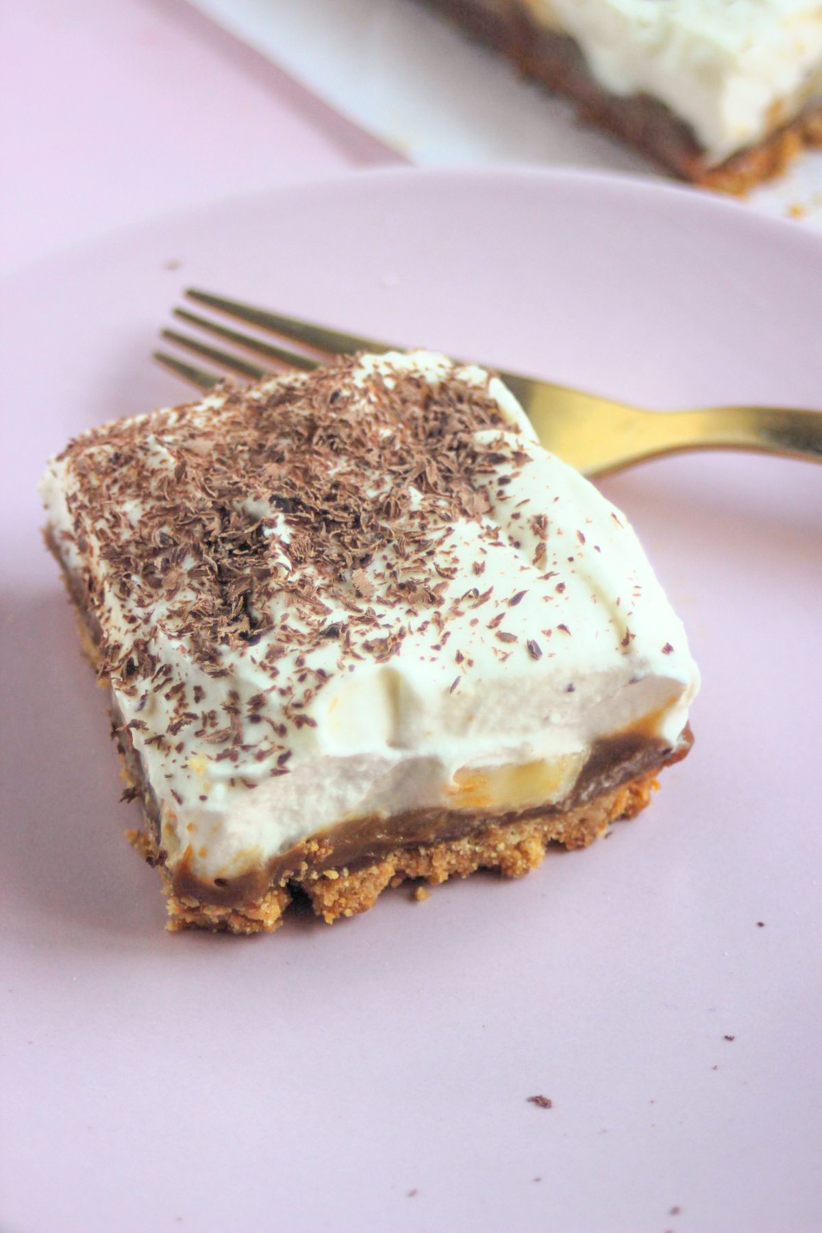 Banoffee pie bar on a pink plate and a golden fork.