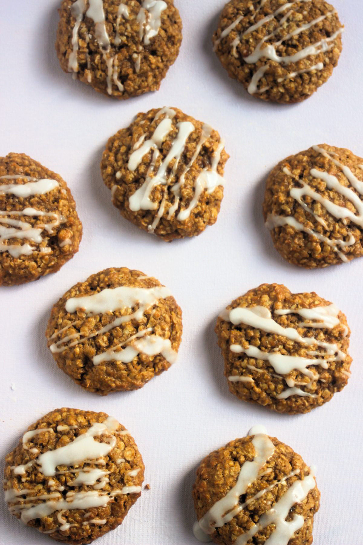 Top view of pumpkin oatmeal cookies iced on white surface.