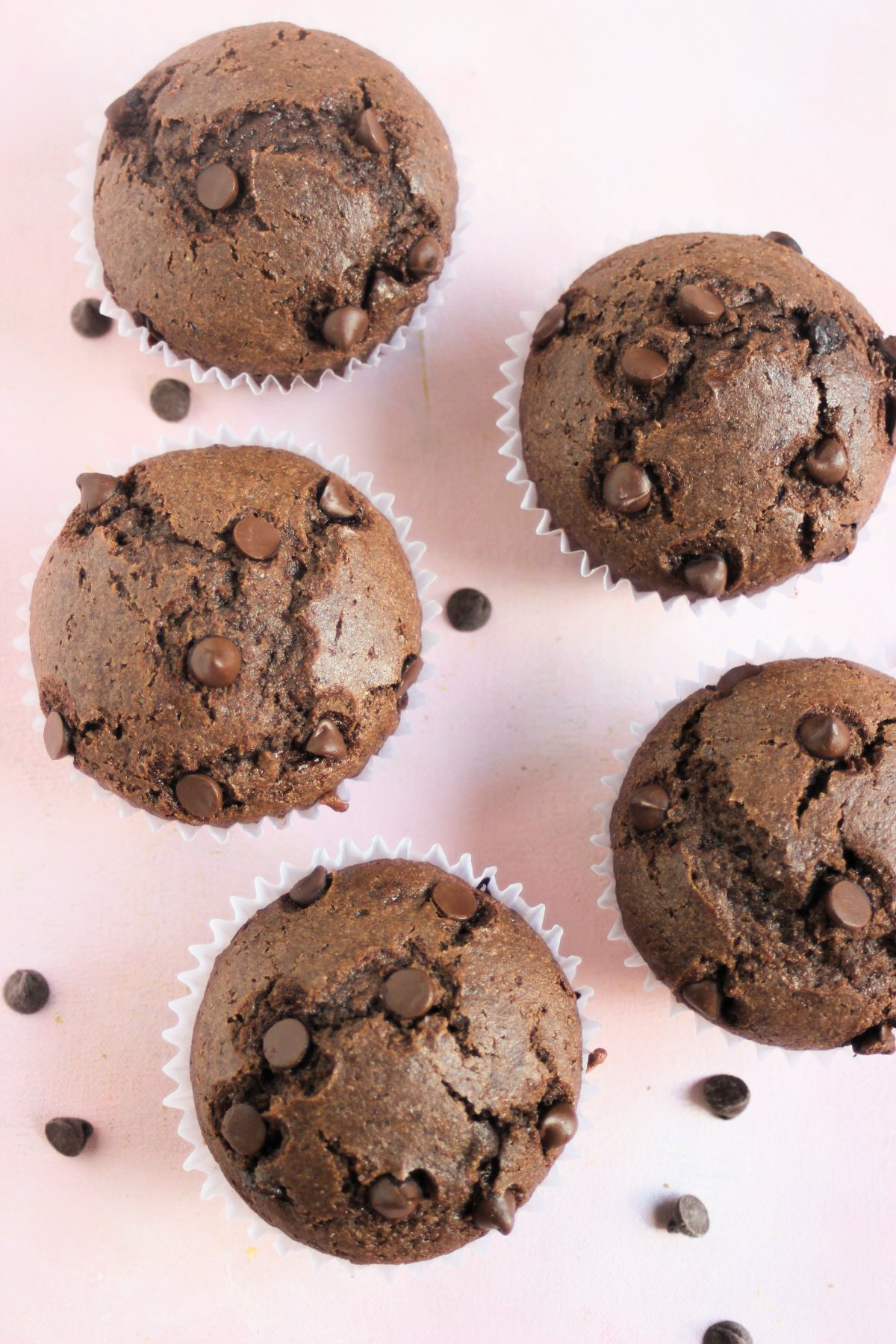 Top view of chocolate buckwheat muffins on a pink surface.