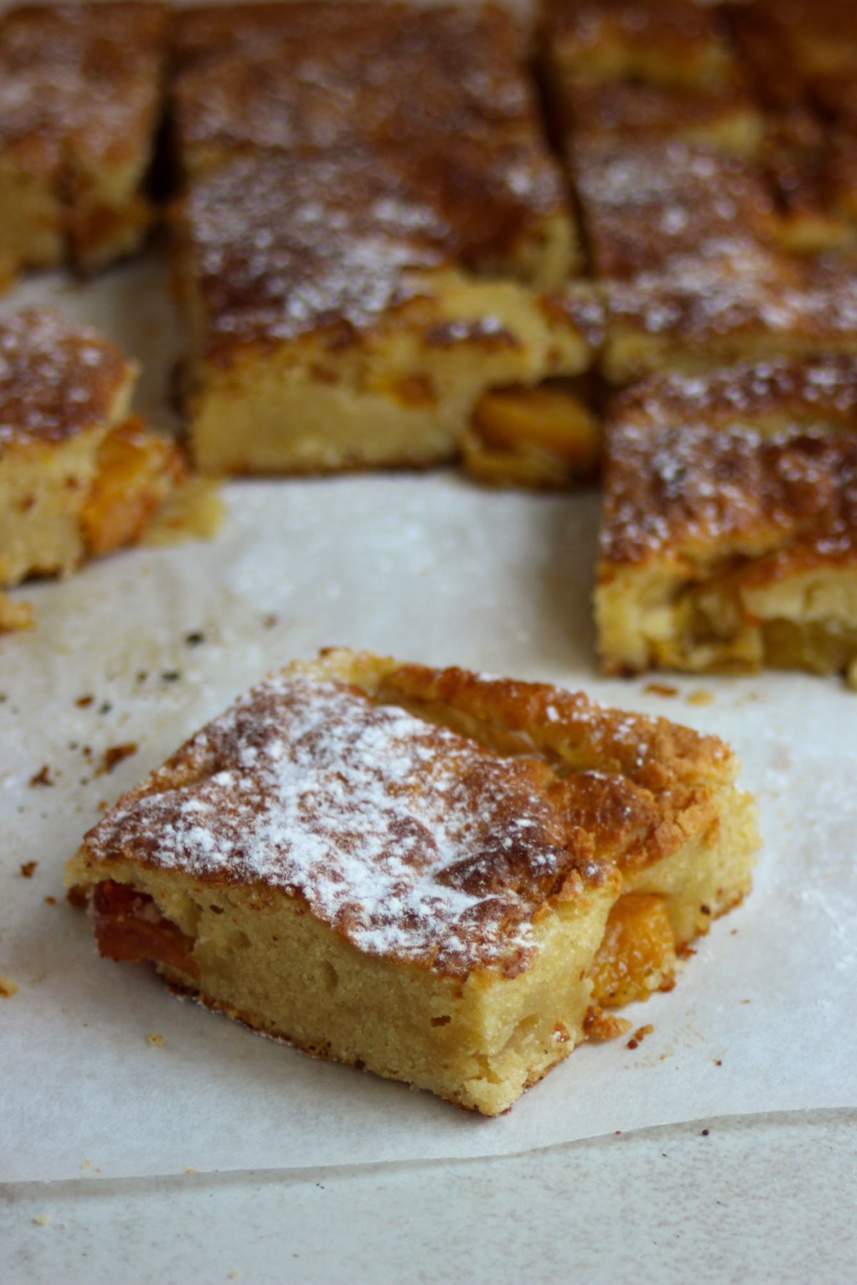 Portions of peach cake on parchment paper.