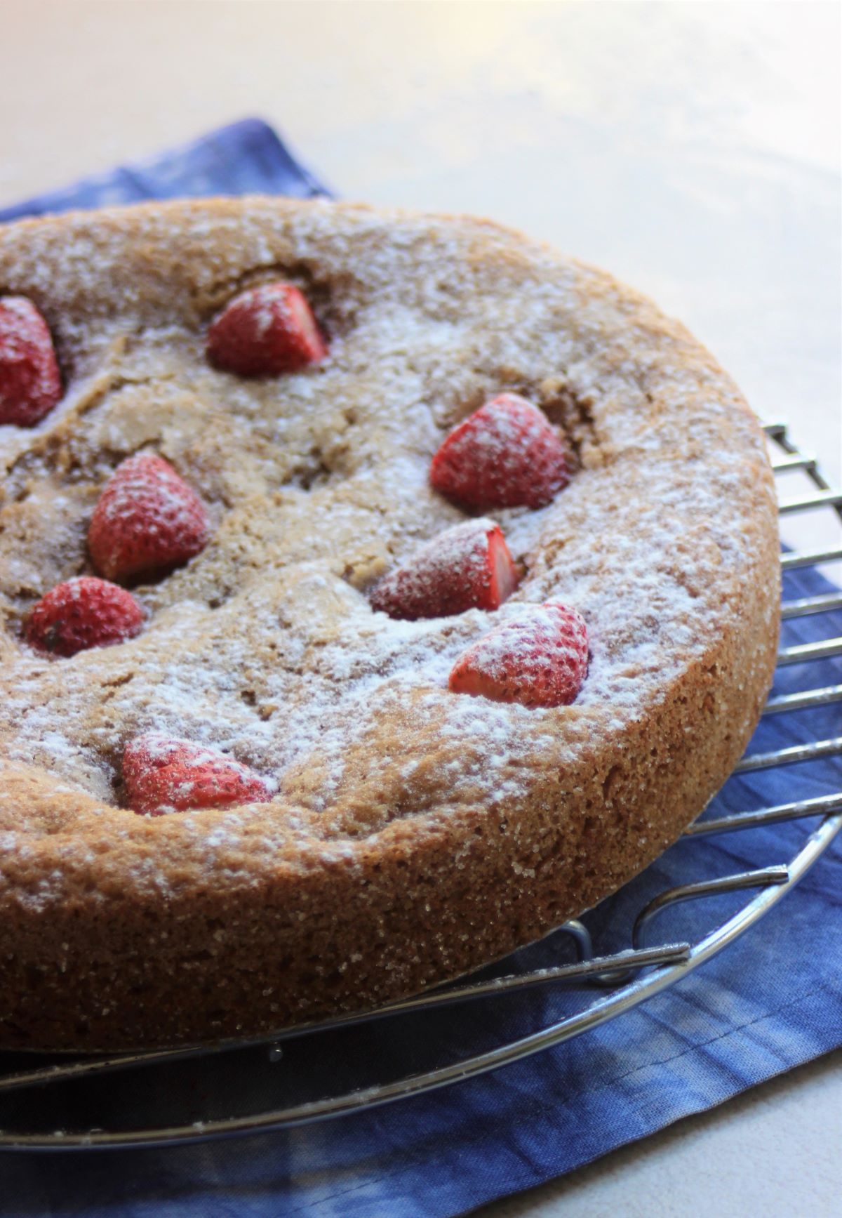 Almond and strawberry cake on a round rack.