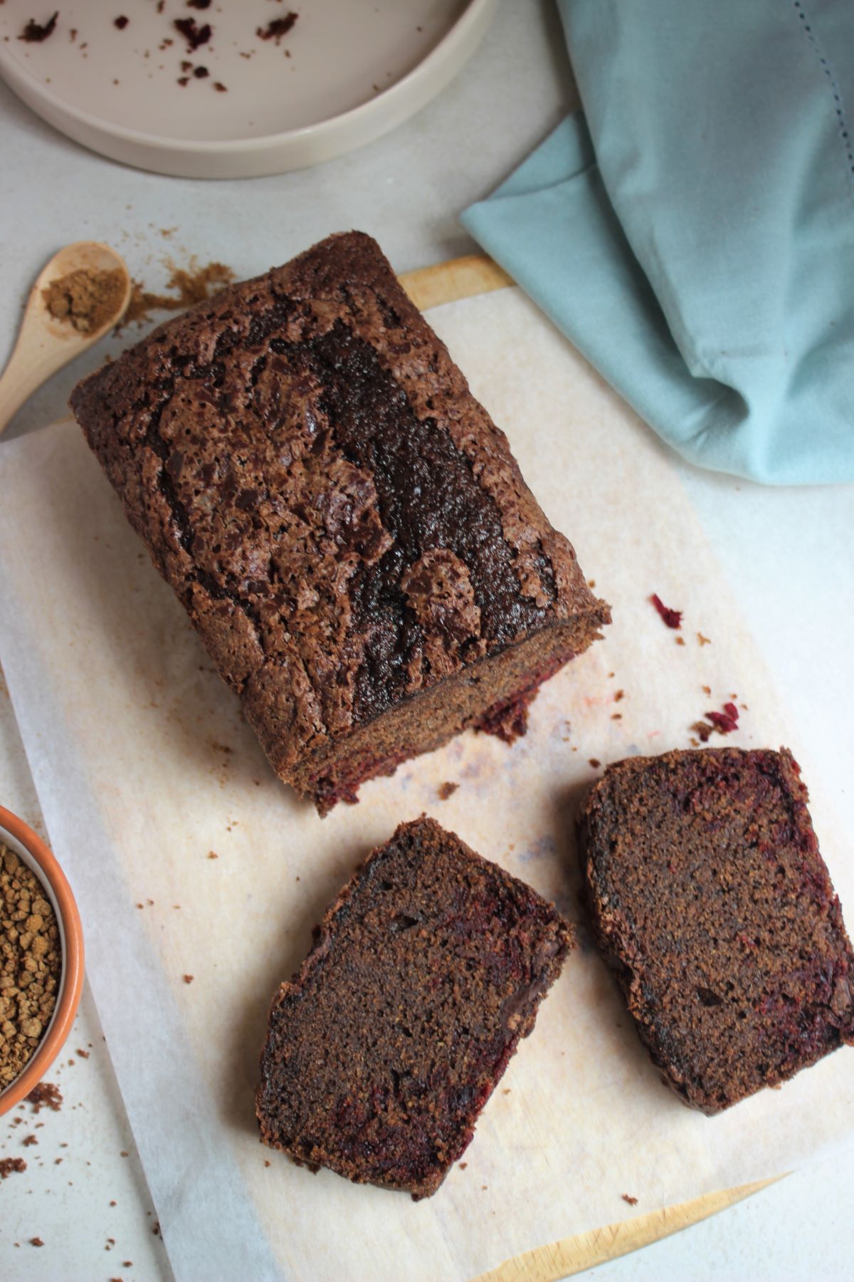 Beetroot and chocolate loaf cake with two slices of it on parchment paper.
