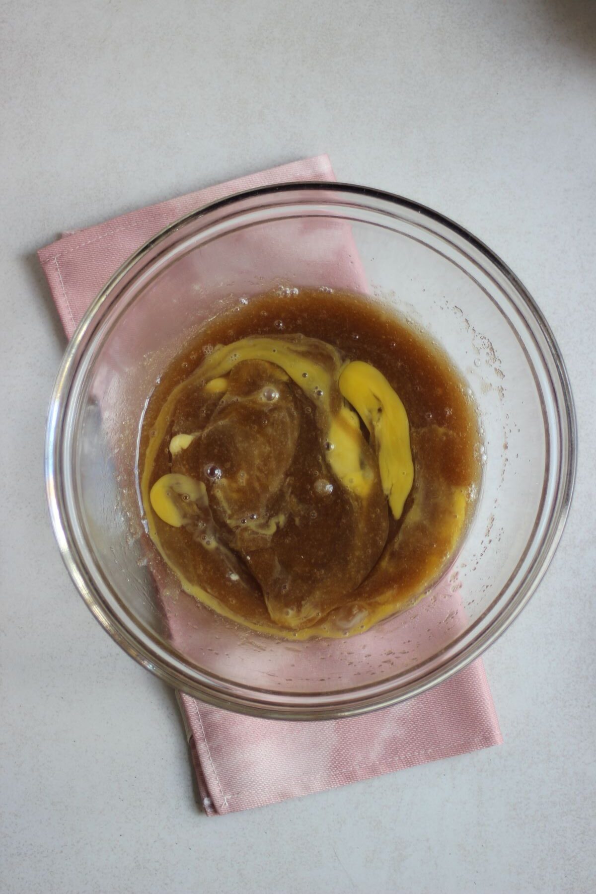 Glass bowl with a brown mixture and eggs mixed.
