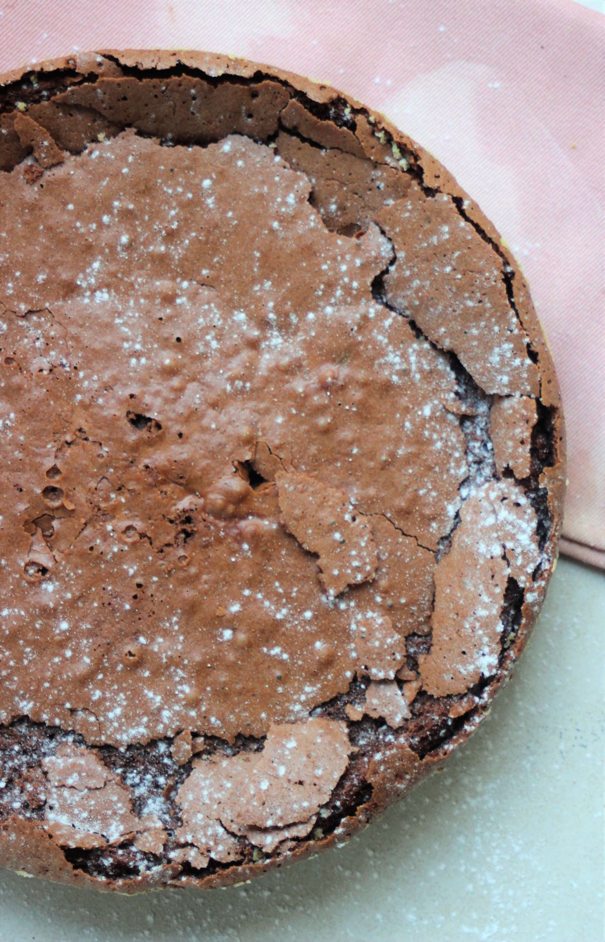 Chocolate cake sprinkled with powdered sugar seen from above.