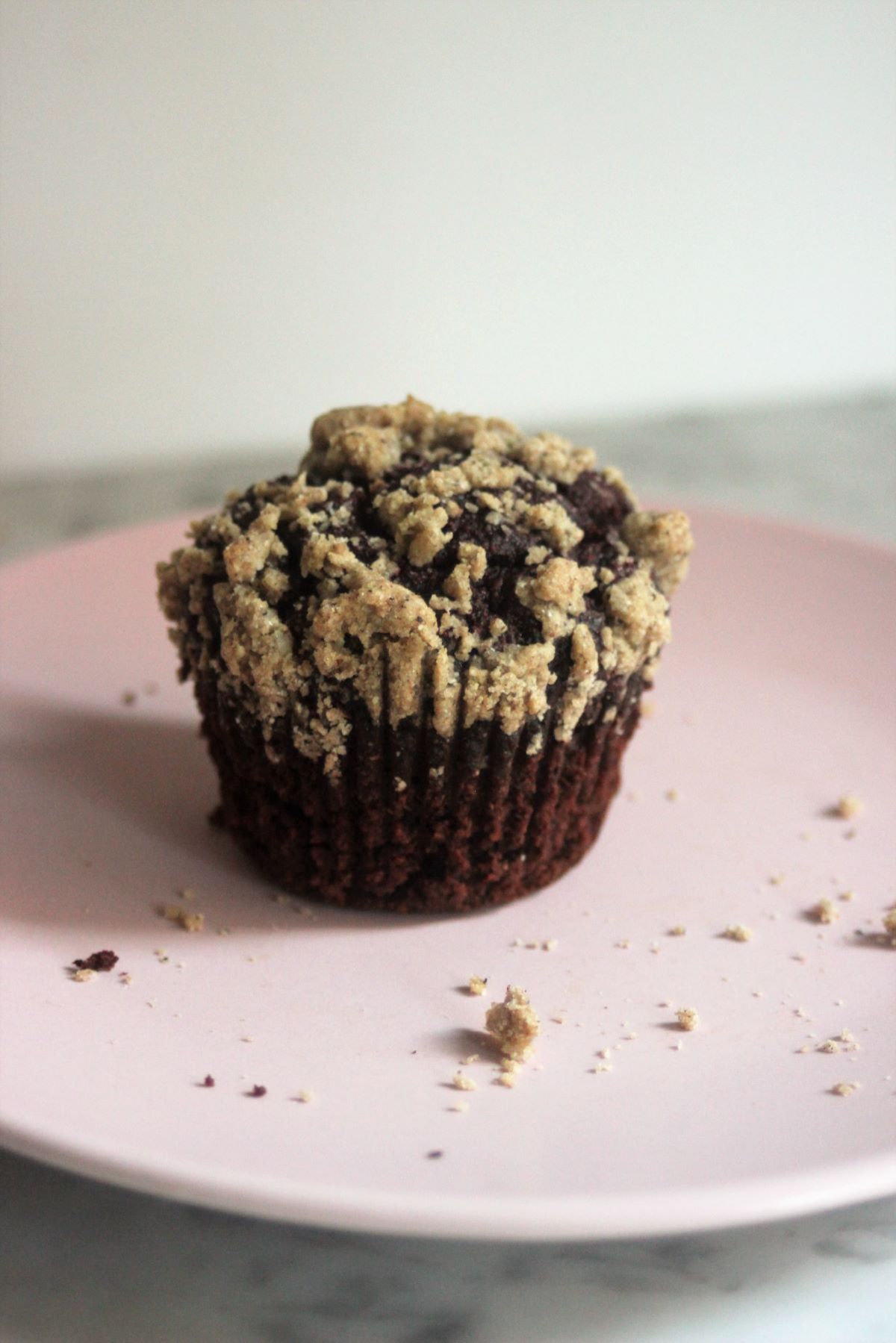 Chocolate beet muffin with brown sugar crumble on a pink plate.
