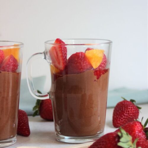 Glass cup with chocolate mousse, strawberries, and peaches. Strawberries on the side..