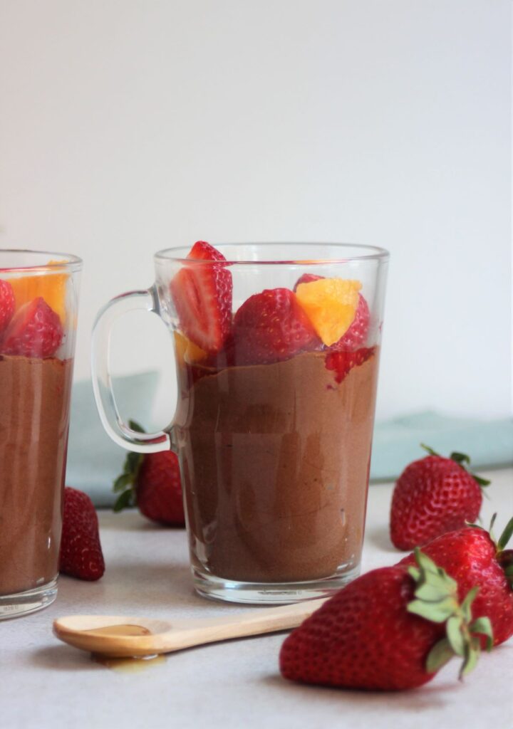 Glass cup with chocolate mousse, strawberries, and peaches. Strawberries on the side..