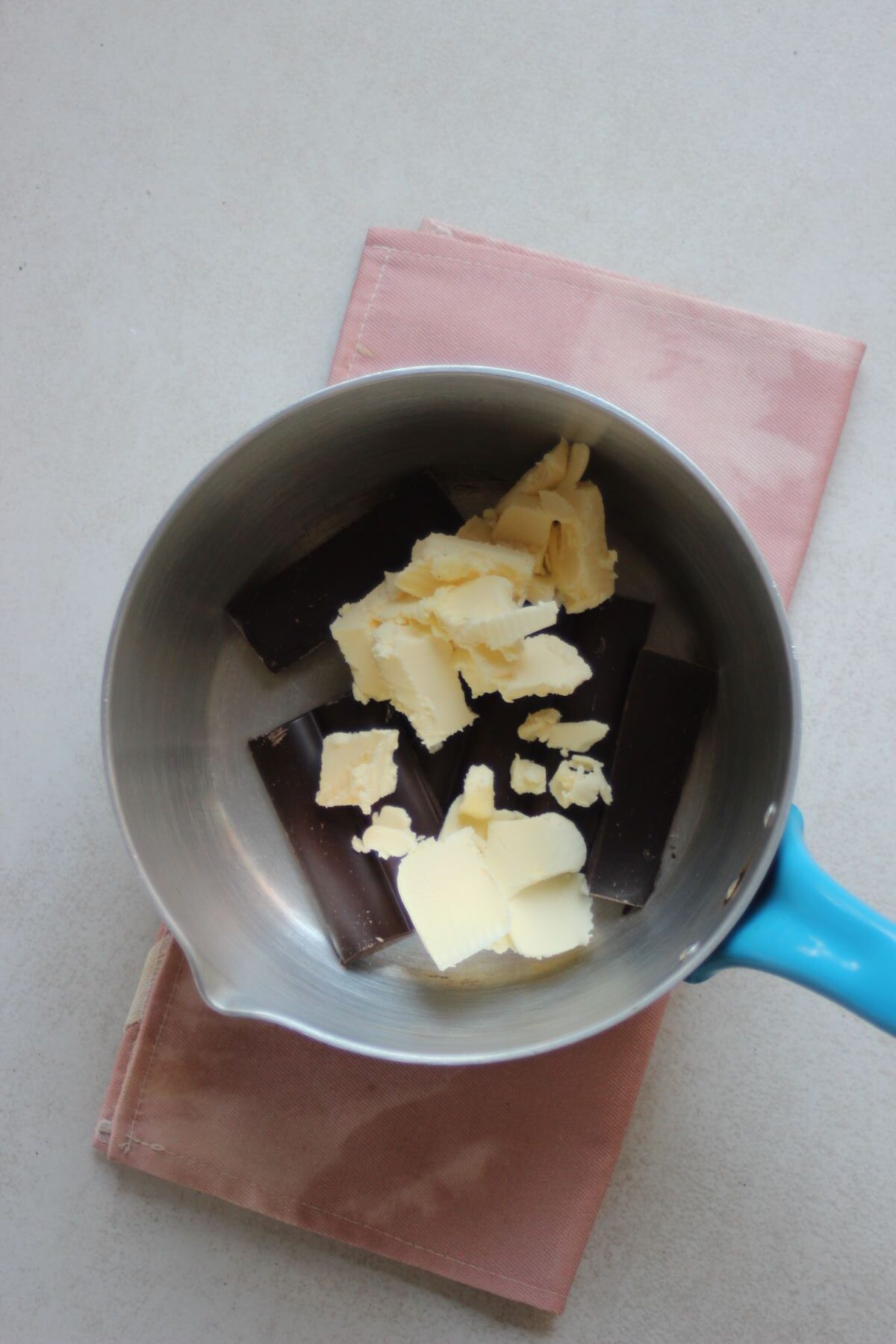 A deep saucepan with dark chocolate bars and pieces of butter.