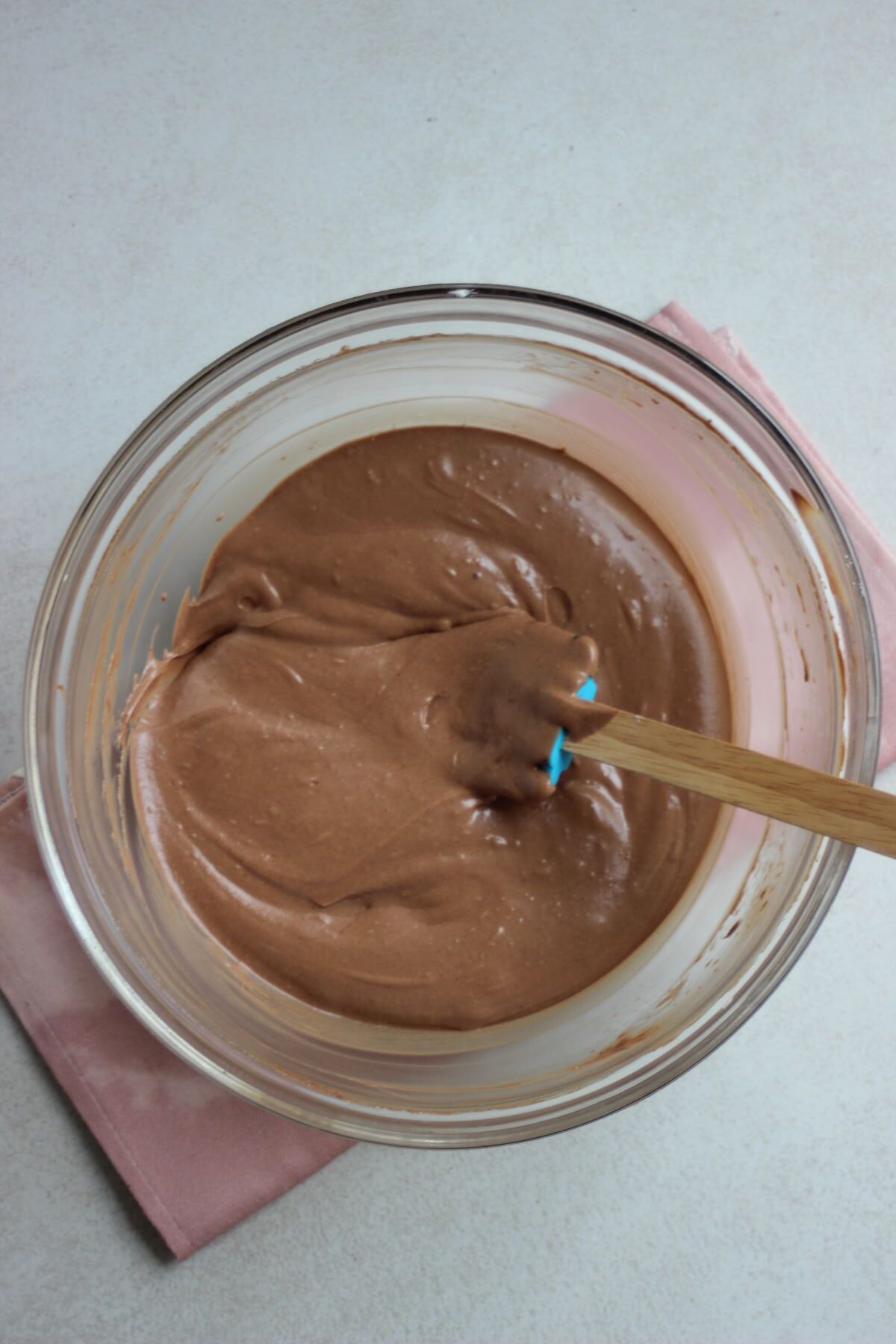 Glass bowl with chocolate mousse and a rubber spatula.