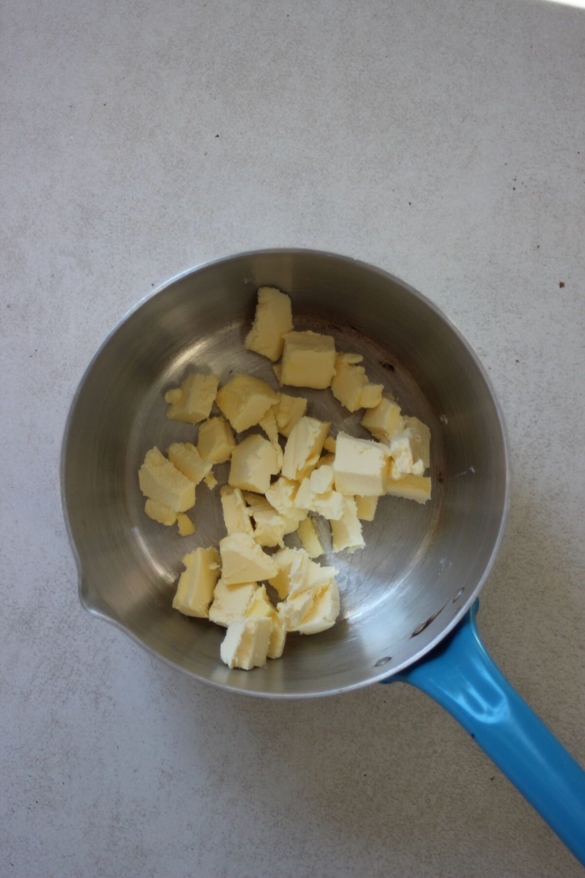 A deep-proof saucepan with pieces of butter.