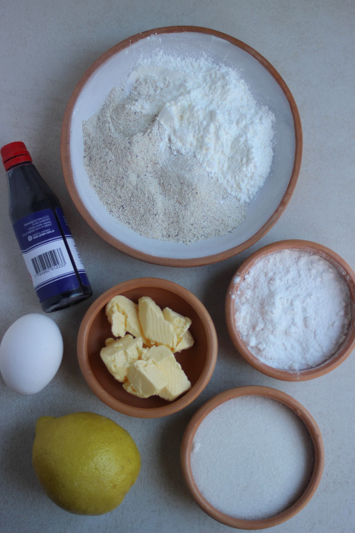 Lemon cookies ingredients on a white surface seen from above.