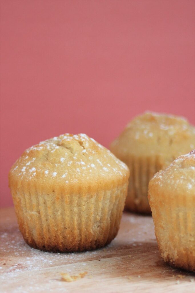 Pear and ginger muffins on a wood surface. Pink background.