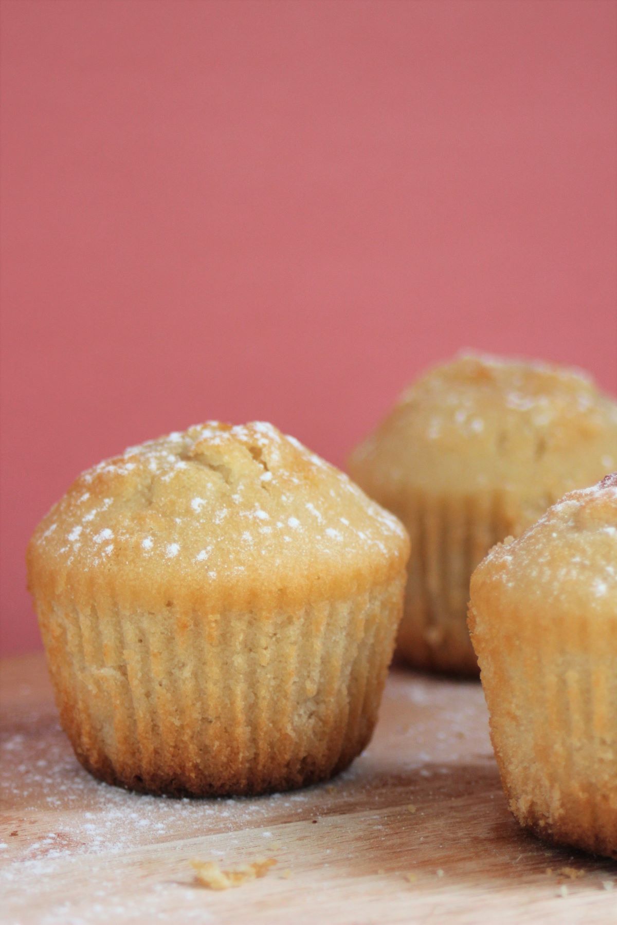 Pear and ginger muffins on a wood surface. Pink background.