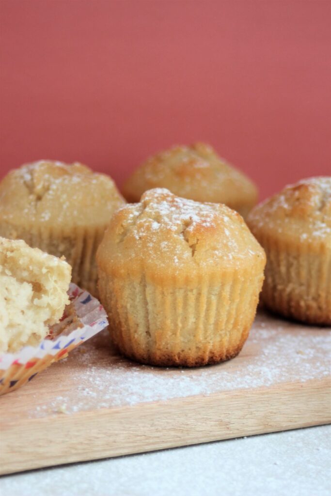 Pear and ginger muffins on a wood board. Pink background.