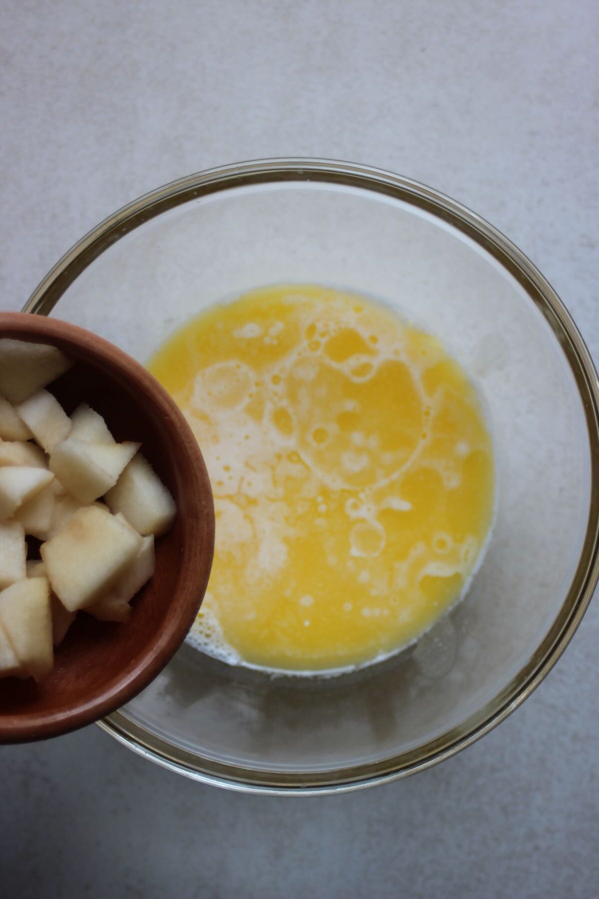 Bowl with chopped pears is about to be poured into a bowl with a yellow liquid.