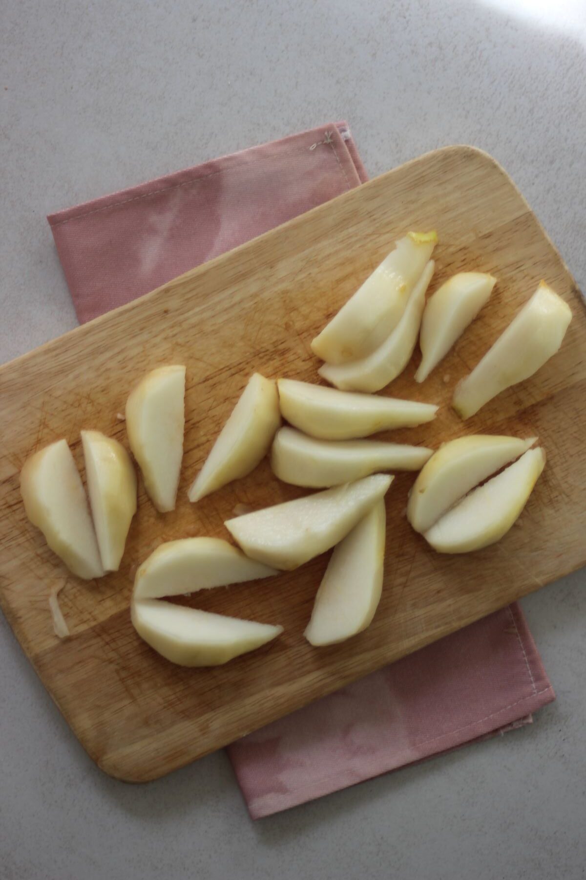 Sliced pears on a wooden table. Pink napkin under the wooden table.