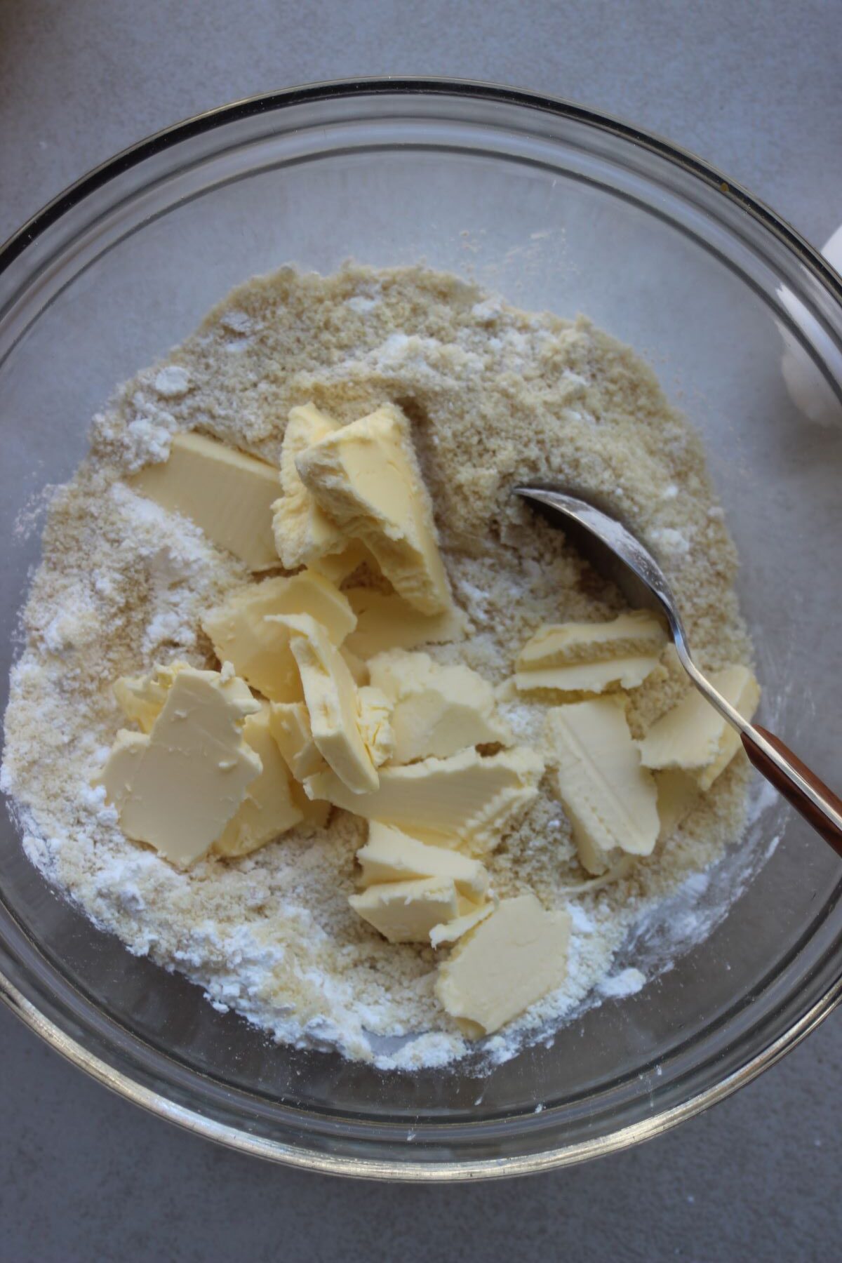 Glass bowl with dry ingredients and chunks of butter.