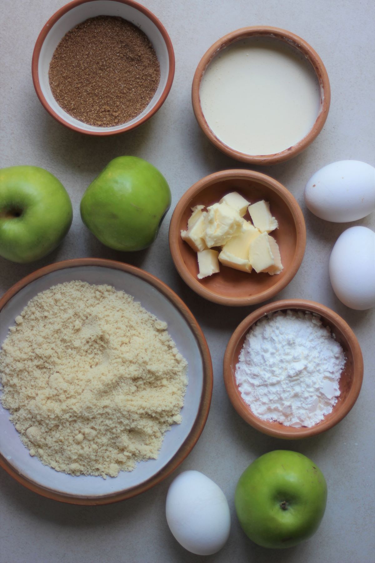 Apple cinnamon cake ingredients on a white surface seen from above.