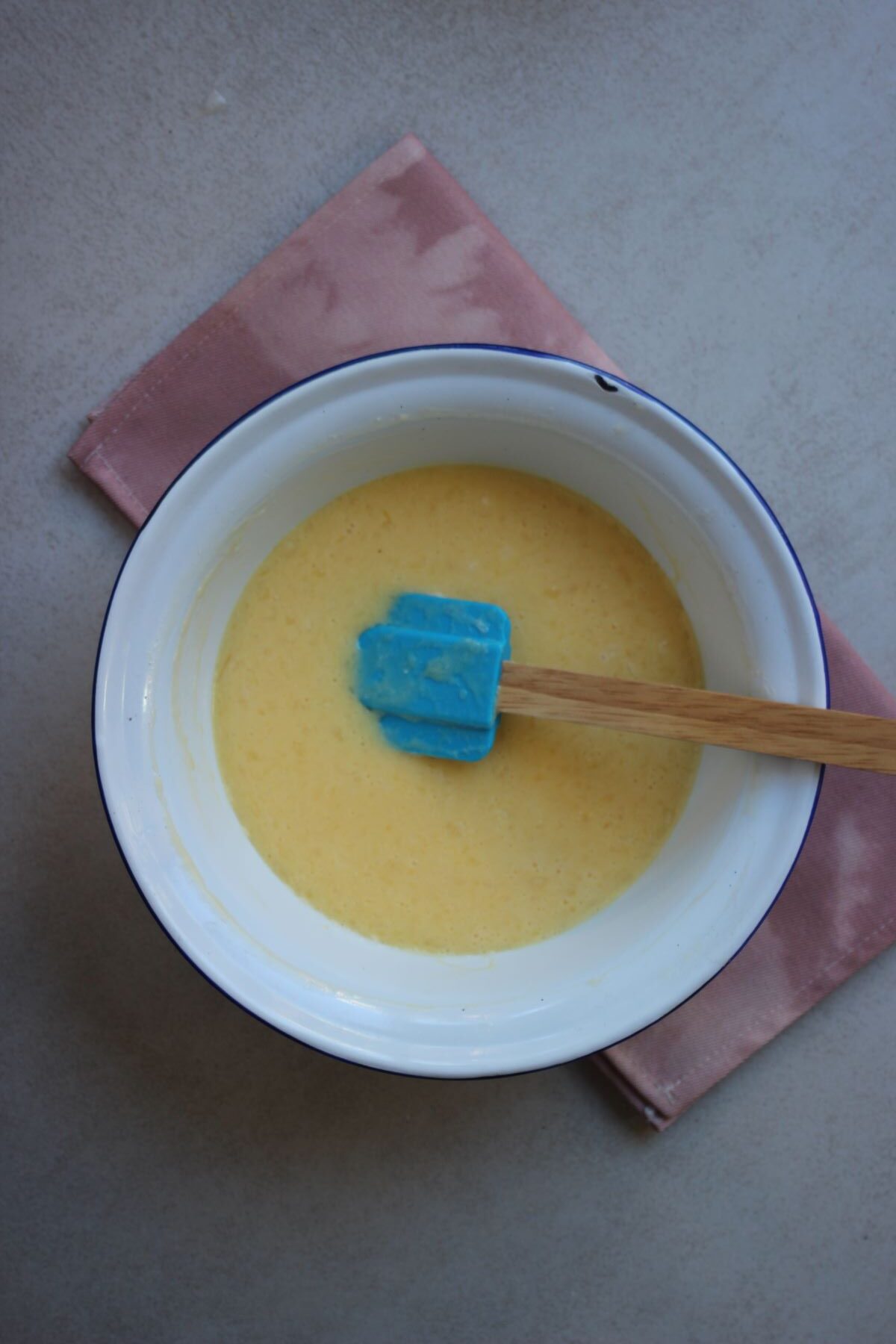 Bowl with a yellow liquid and a rubber spatula.