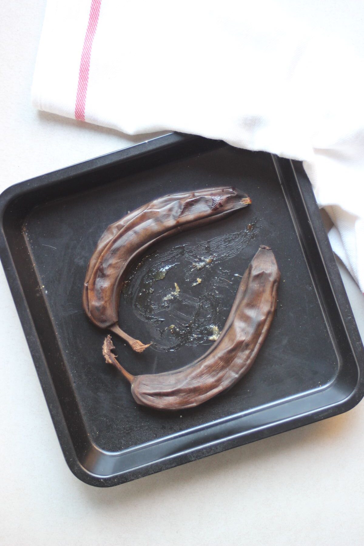 Two burned bananas on a baking pan.