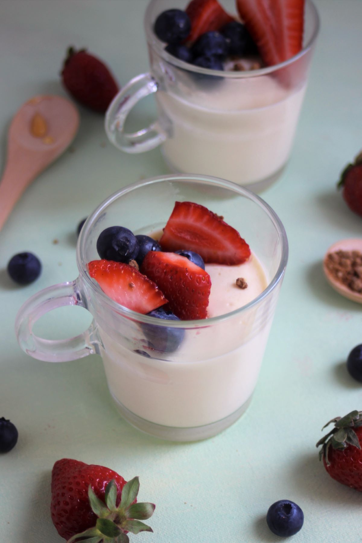 Glass cup with vanilla panna cotta, strawberries, and blueberries.