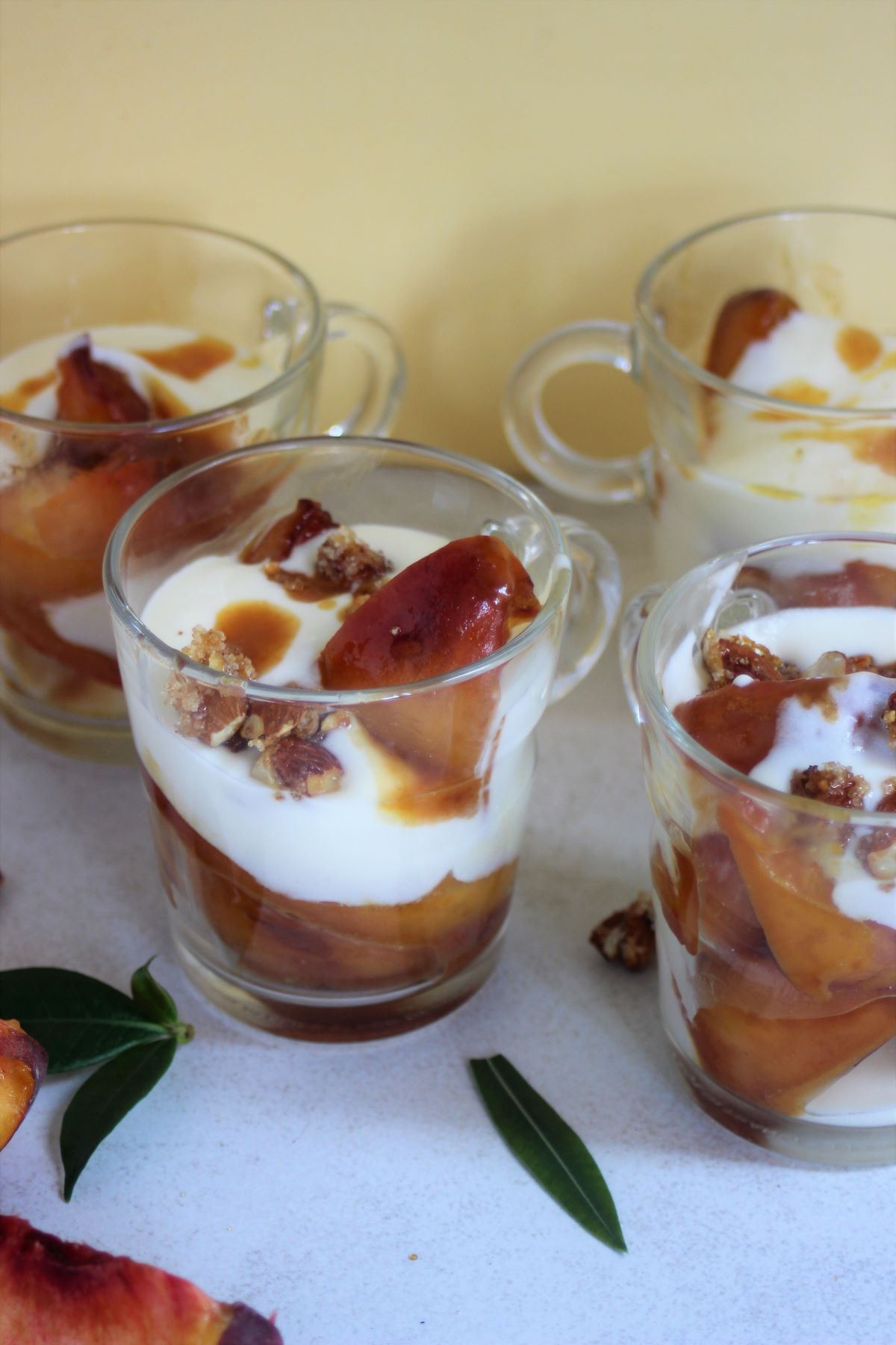 Glass cups with cream, peaches, and caramelized almonds.
