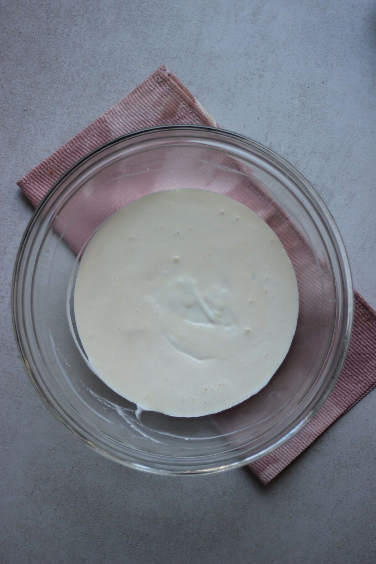 A glass bowl with a white liquid. Pink napkin under the bowl.