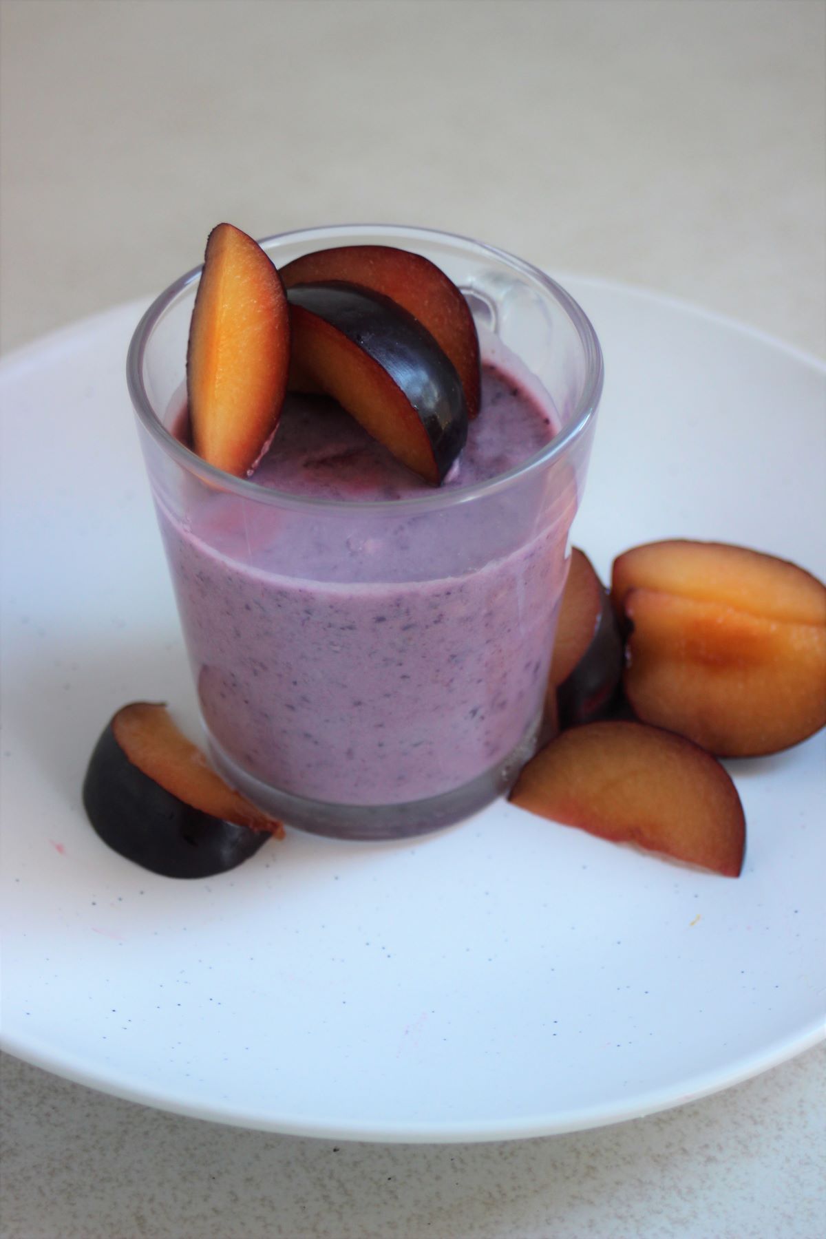 Yogurt and blueberries panna cotta in a glass jar with fresh plums.