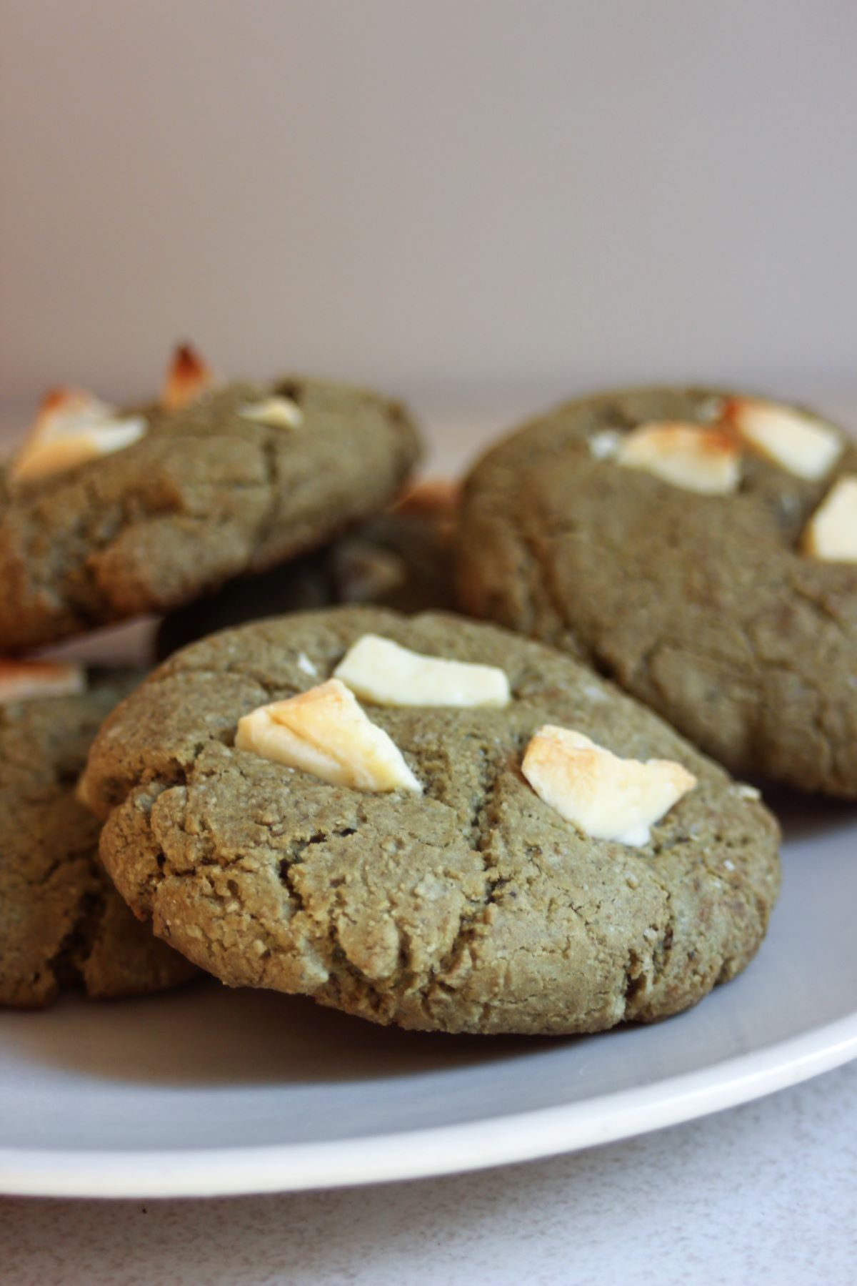 Matcha cookies with white chocolate chunks on a white plate.