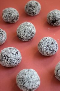 Brigadeiros with shredded coconut on a pink surface.