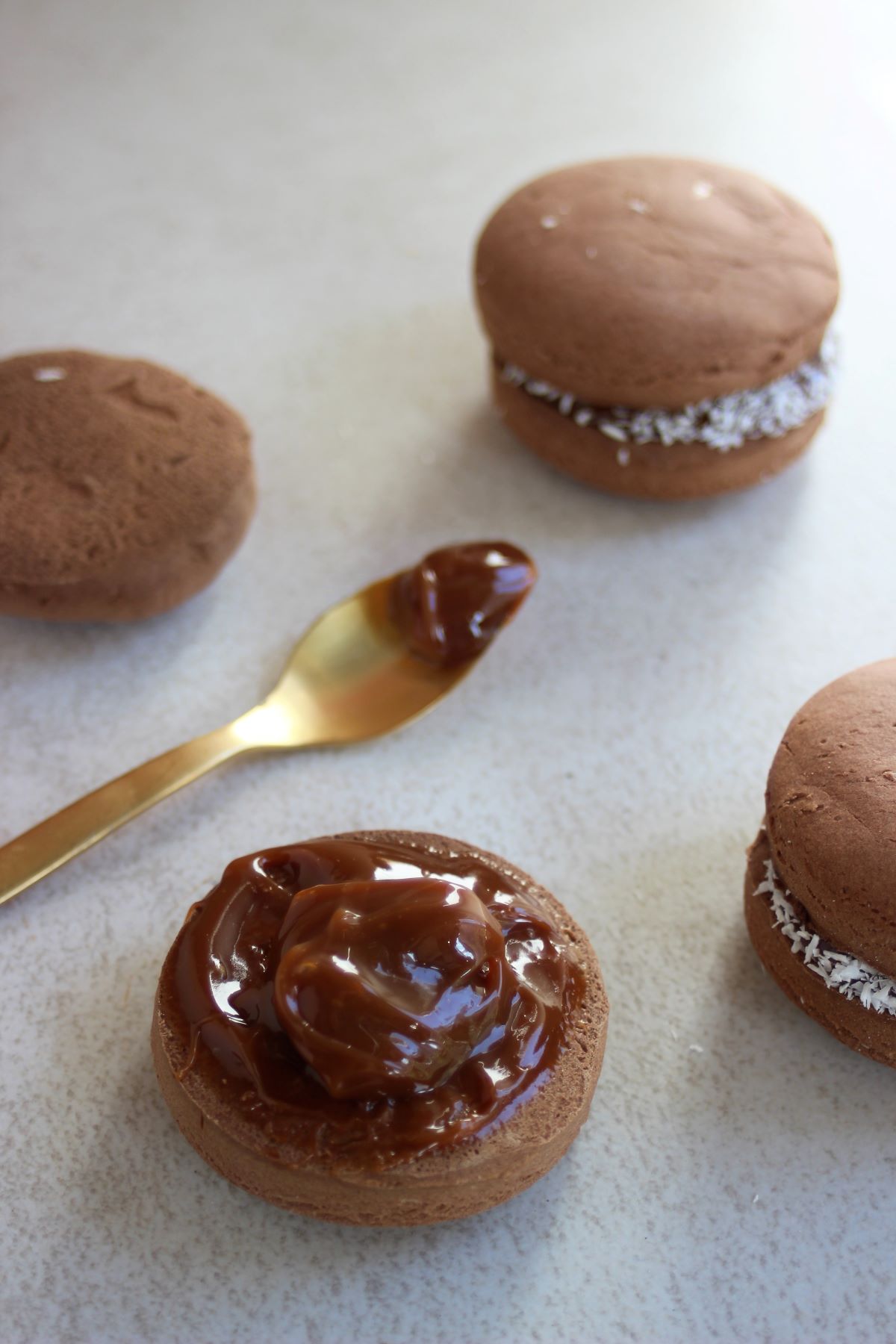 Chocolate biscuit with dulce de leche. Spoon with dulce de leche and two chocolate alfajores around.