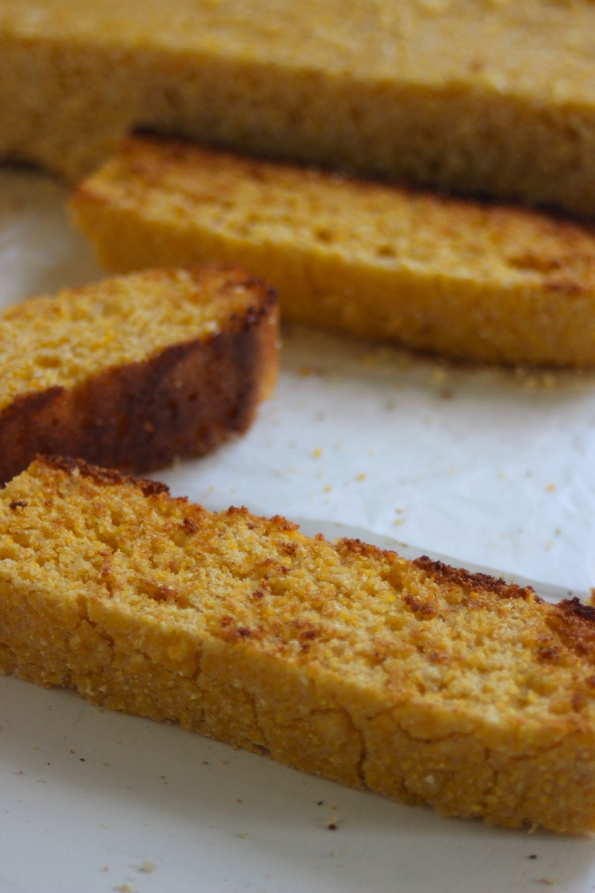 Slices of corn bread on a white surface.