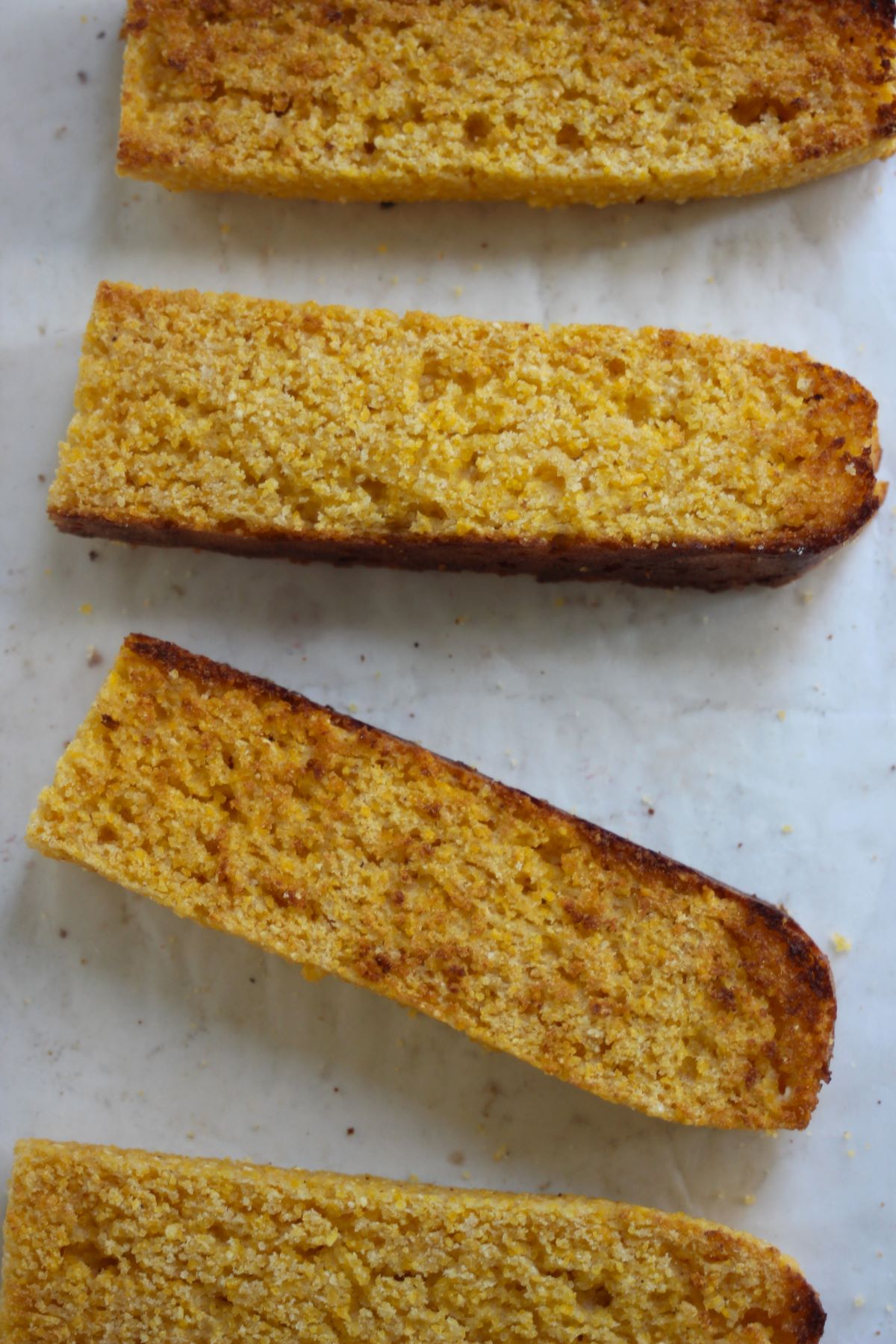 Slices of corn bread seen from above on a white surface.