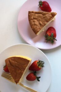 Two plate with two portions of japanese cheesecake and strawberries seen from above.