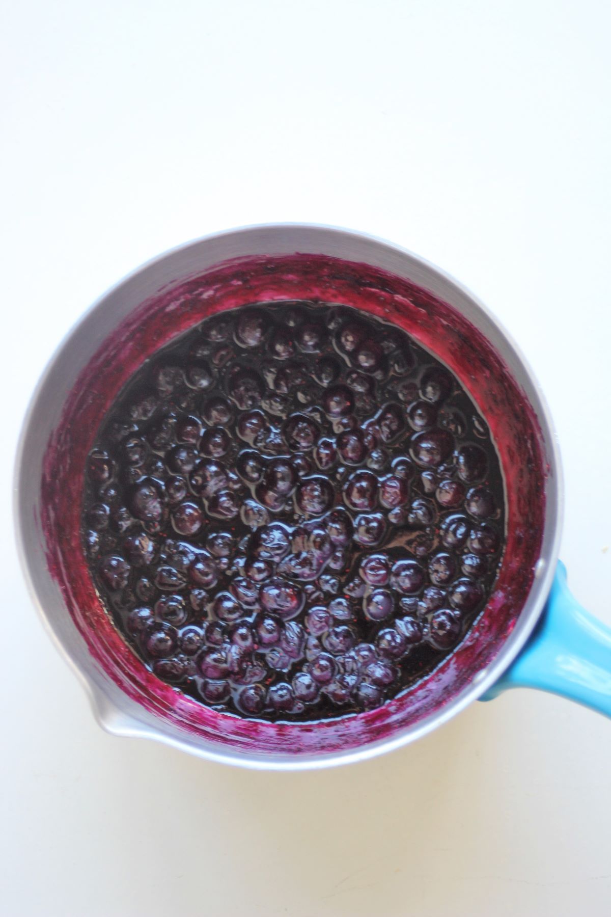 A deep saucepan with blueberry sauce seen from above.