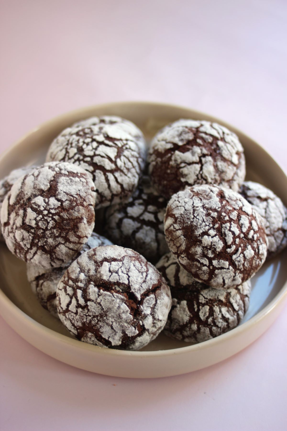 Many chocolate crinkle cookies on a plate.