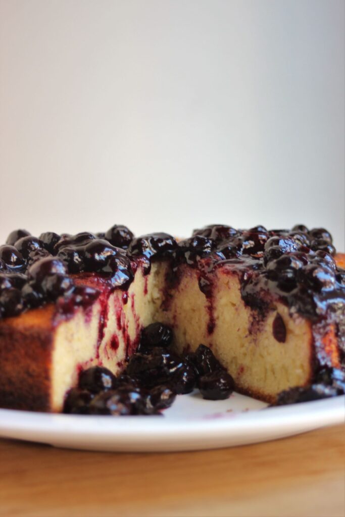A ricotta cake, without a piece, with blueberry sauce, view from the front.