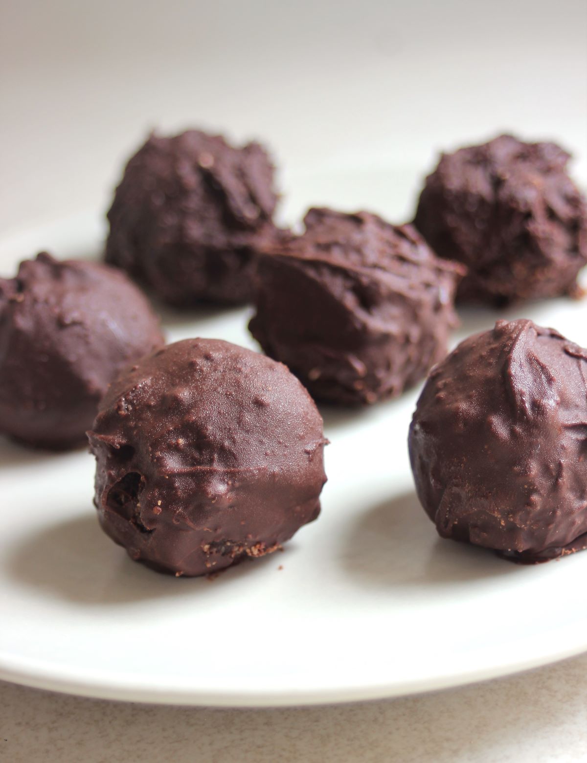 Chocolate peanut butter balls on a white plate.