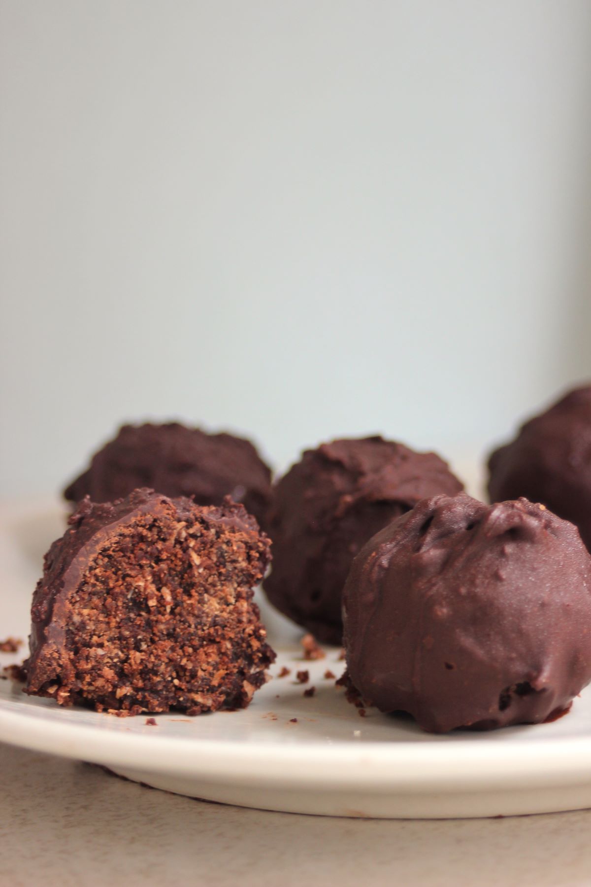 Chocolate peanut butter balls on a white plate. One is cut in half.