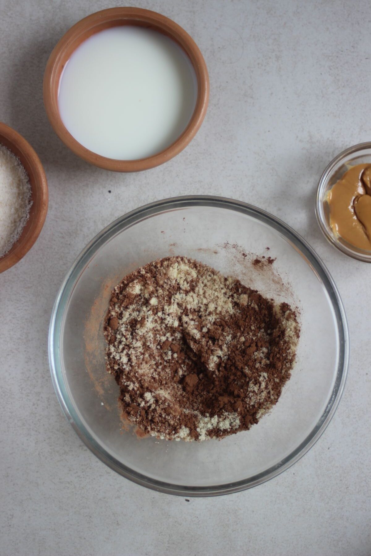 Glass bowl with a mix of flour and a tiny bowl with milk.