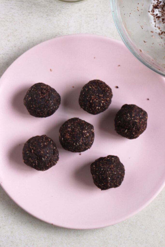 Chocolate peanut butter balls, without the chocolate coating, on a pink plate.