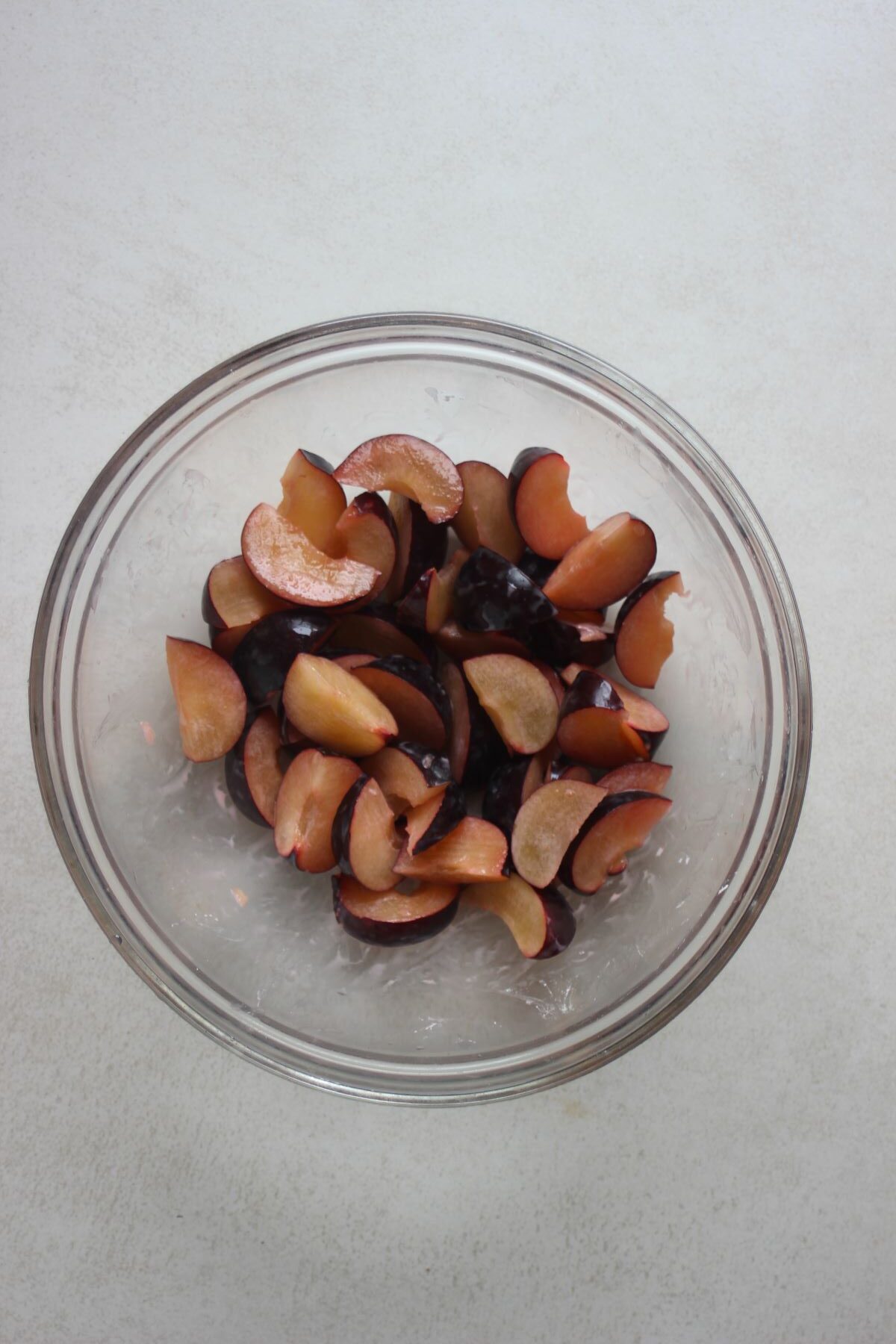 Glass bowl with sliced plums.