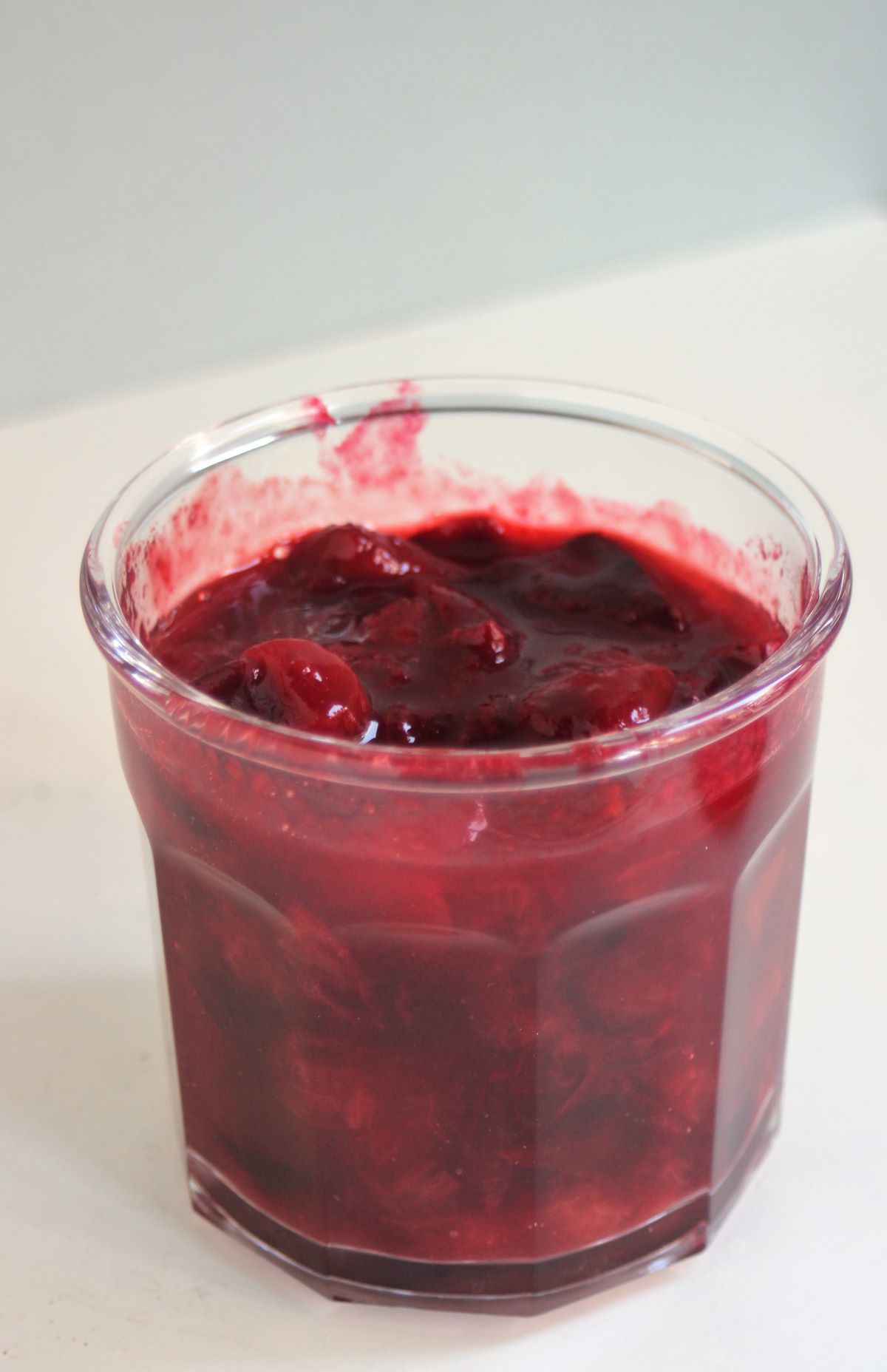 Jar with plum sauce on a white surface.