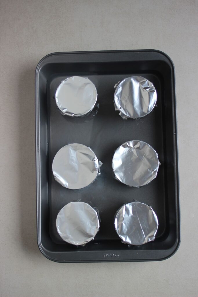 Baking sheet with flan molds covered with aluminum.