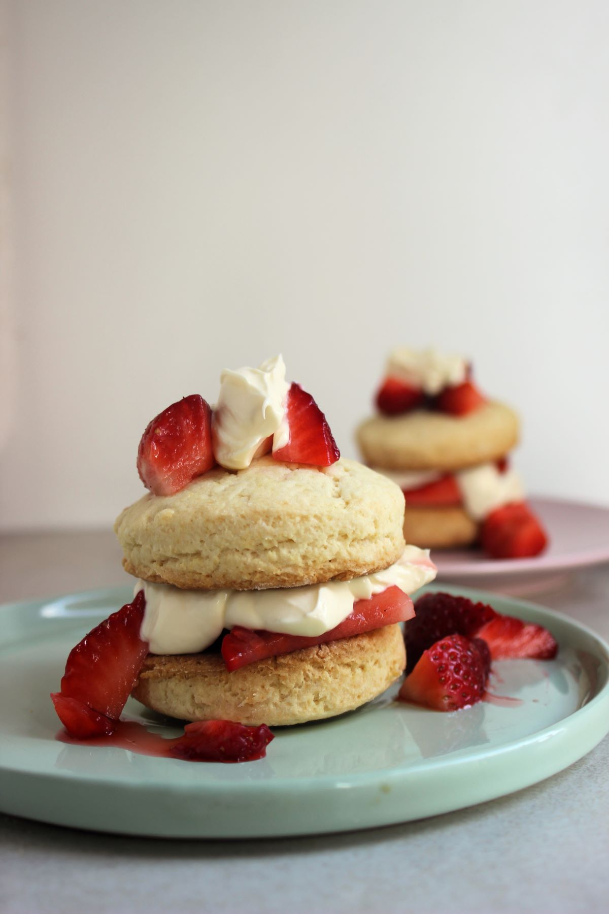Strawberry shortcake on a plate and more strawberries on the sides. Another shortcake behind.