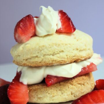 Strawberry shortcake on a white plate and strawberries on the sides.