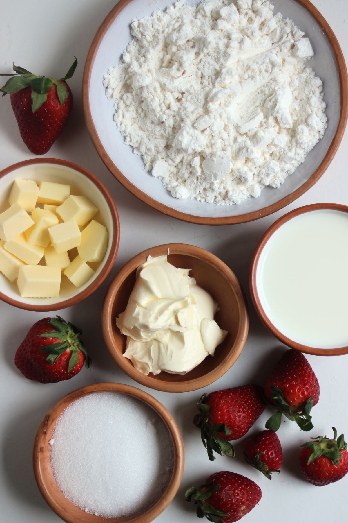 Strawberry shortcake ingredients in different plates, seen from above.