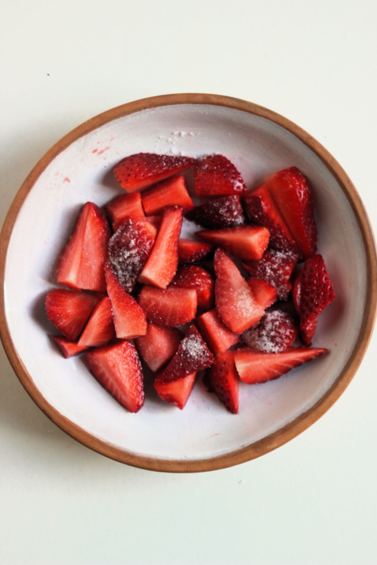Sliced strawberries with sugar on a plate.
