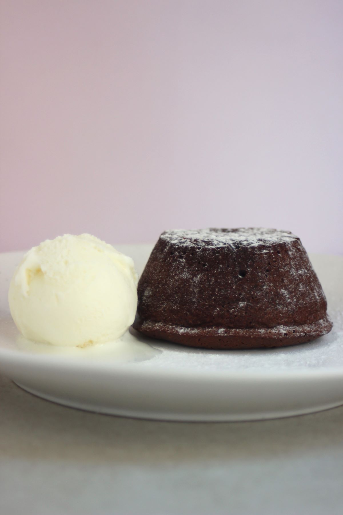 White plate with molten lava cake and a scoop of ice cream.